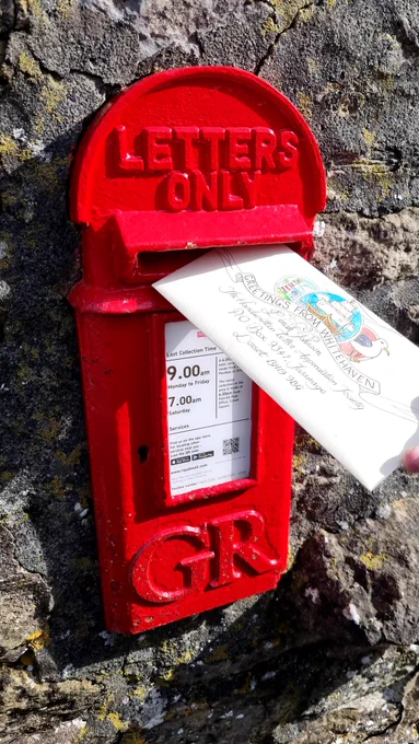 Painted letter being posted in a bright red GR postbox.