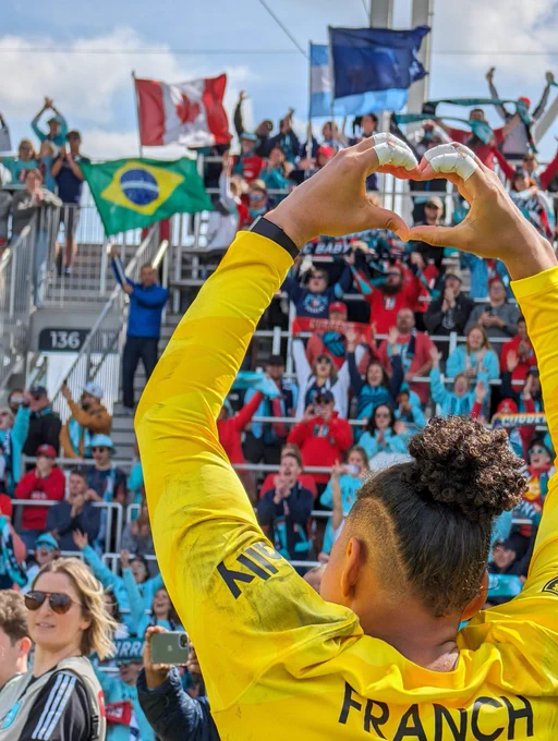 Photo of Franch from behind holding up heart hands to our supporter section