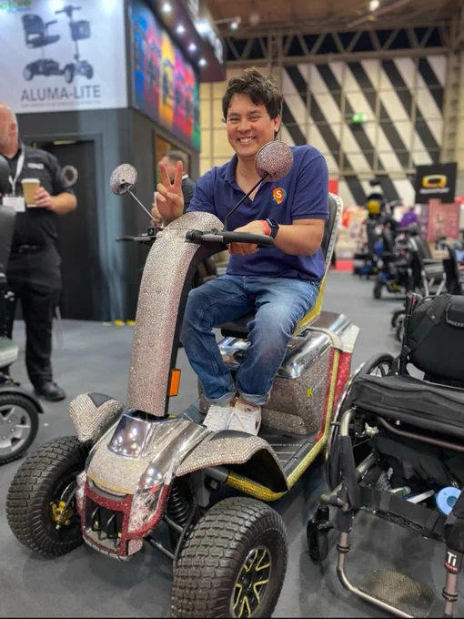 A smiley man sitting on a sparkly mobility scooter