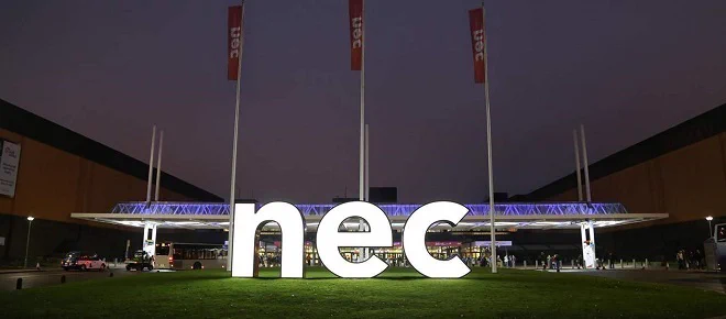 The NEC entrance at night time with large light up letters n e and c. 