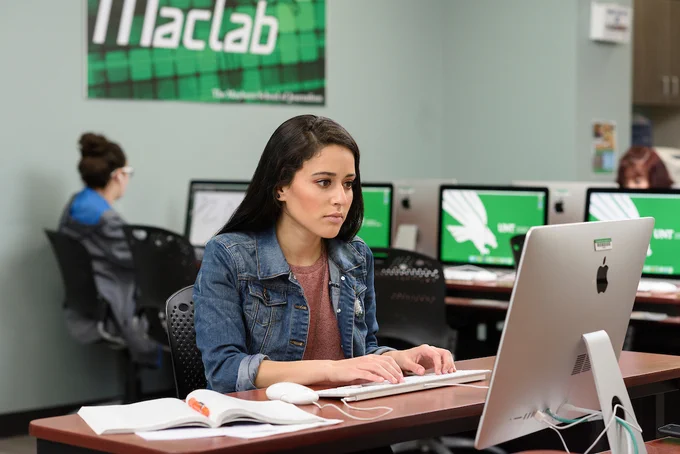 UNT student sitting at a desktop inside a UNT computer lab.
