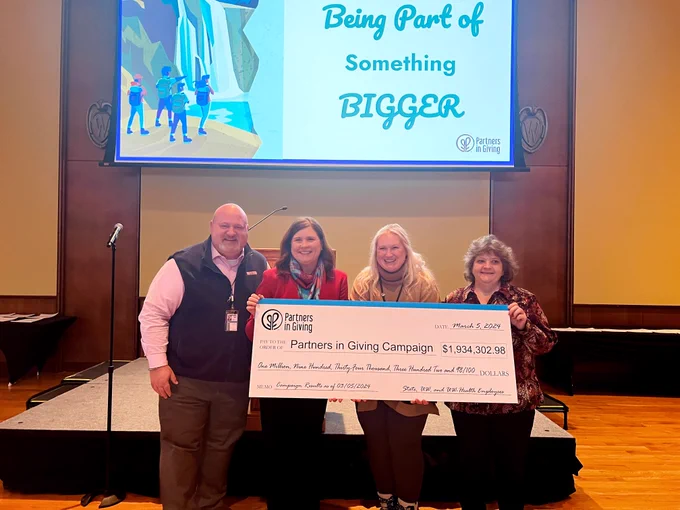 DOA Secretary Kathy Blumenfeld and Assistant Deputy Secretary Diana Maas (center) hold a check in celebration of the total funds raised for the Partners in Giving employee campaign of 2023.
