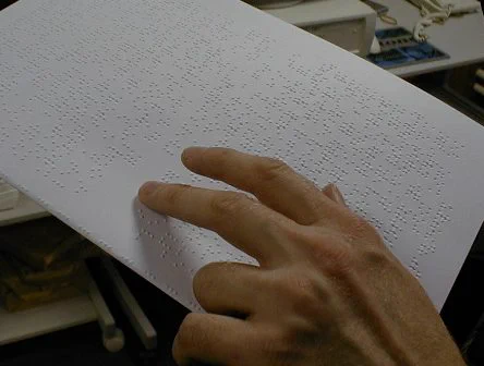 Person reading Braille using his hand