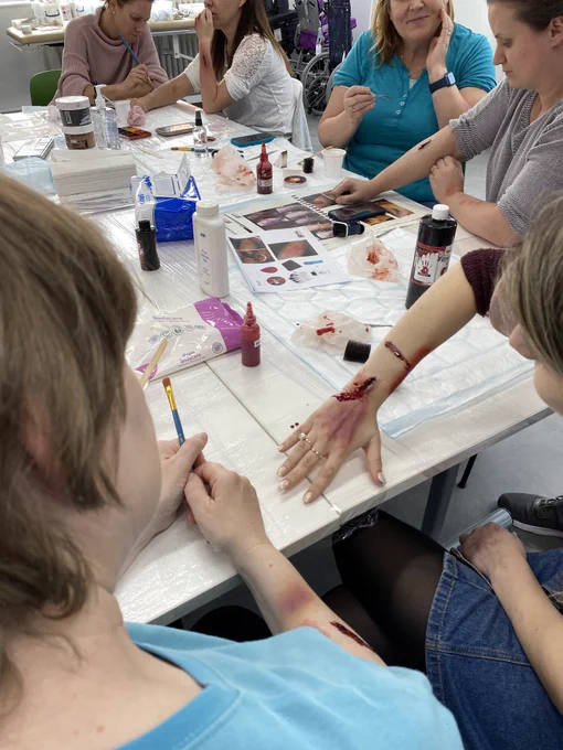 Image of learners creating moulage wounds on each other using make up. 