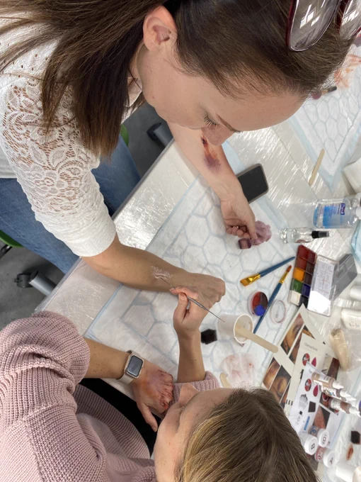Image of learners creating simulated wounds on each other using moulage make up