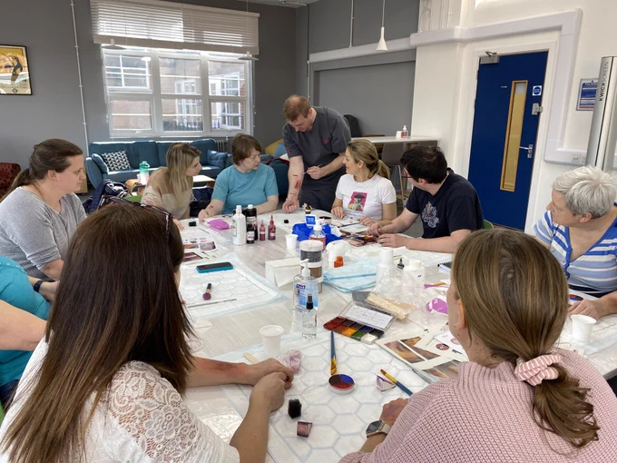 Image of one of our simulation technicians teaching the group how to create a moulage wound for simulation