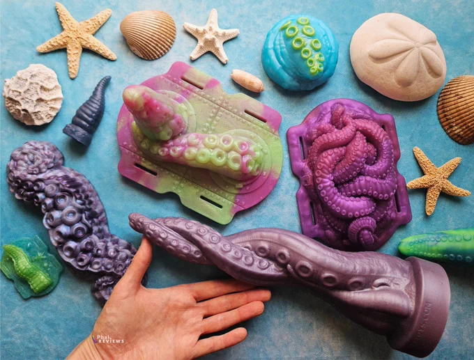 5 tentacle grinding toys of different sizes and colors, on blue background with seashells around 