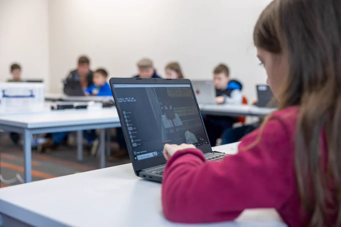 Girl playing Minecraft on a laptop
