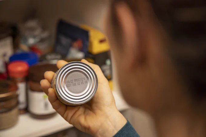 Someone looking at the date on the bottom of a food tin