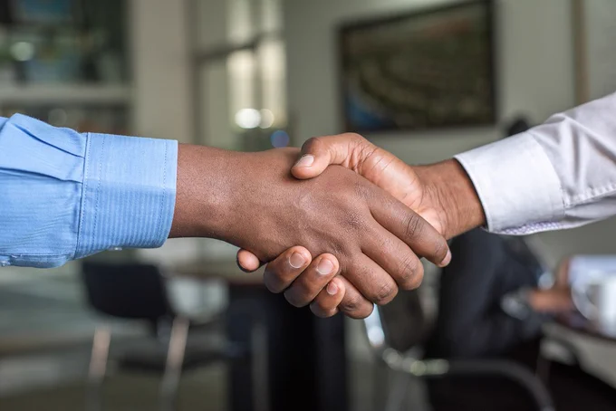 A close up of  two people shake hands in an office environment