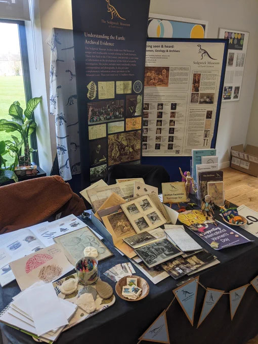 Sedgwick Museum display including roller banner, facsimiles, postcards, and fossil rubbing activity. 
