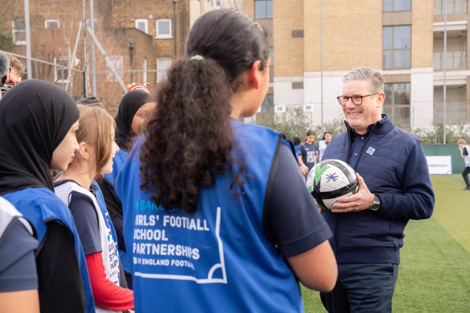Picture of Keir Starmer on football pitch speaking to young girls about football and the importance of sport to them
