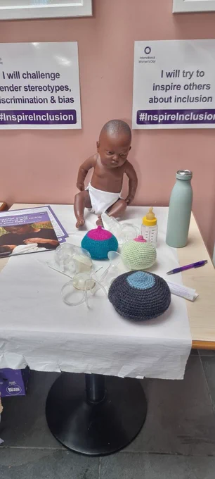 Table with baby doll on top alongside breastfeeding accessories. 