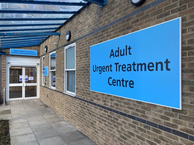 An image taken outside of the Adult Urgent Treatment Centre (UTC) at Lister Hospital in Stevenage, Hertfordshire. Various signs with the name of the UTC are visible on a light blue background, symbolising the Light Blue Zone of the hospital - where the UTC is located.