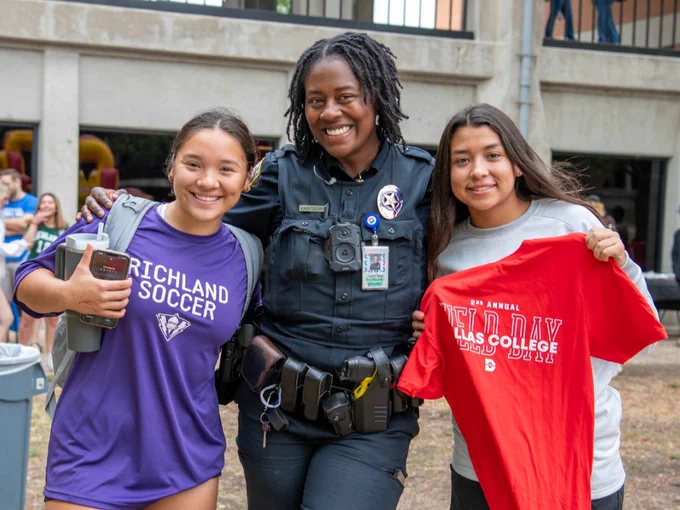 Two female students posing with a campus police officer.