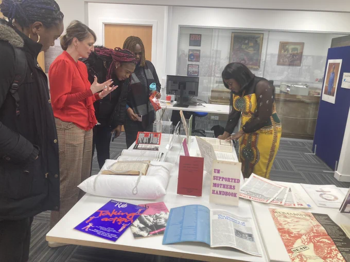 A group of students and their tutor looking at a display of archival resources relating to women’s activism in the GCU Archive Centre