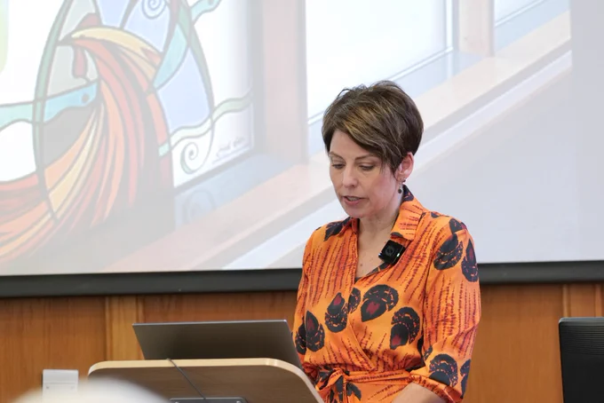 Me at the lectern reading my notes in an orange and brown dress