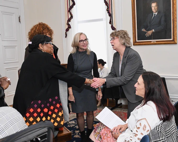 Circle of 5 women with Secretary Beatty shaking hands with one woman