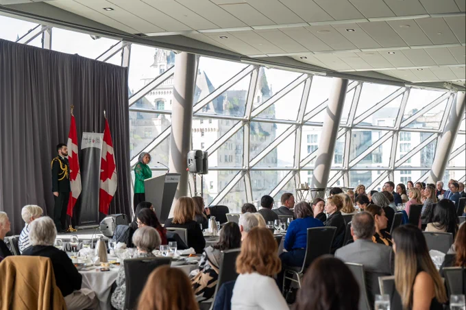 Governor General Simon speaking into a microphone to an audience.