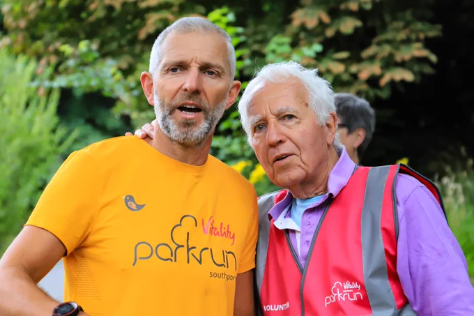 Simon in parkrun apricot T-shirt with his dad, Leo in his trademark purple