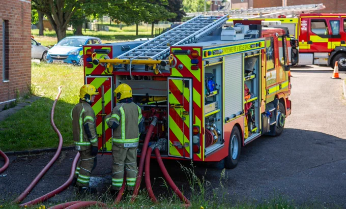Warwickshire Fire & Rescue Fire Engine with two fire fighter at the back.