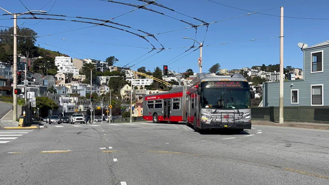 IMC bus 7283 rounding the corner at market and Clayton. The bus is in muni grey/red colors with its trolley poles on the wires