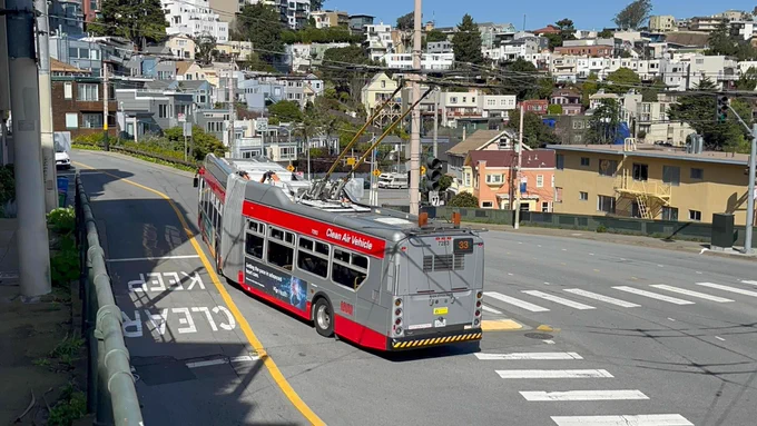 IMC bus 7283 after turning the corner at market and Clayton. The bus is in muni grey/red colors with its trolley poles on the wires