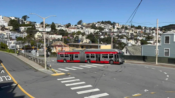 IMC bus 7283 about to turn the corner at market and Clayton. The bus is in muni grey/red colors with its trolley poles on the wires