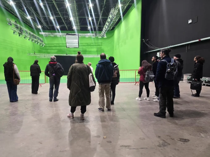 12 people on a tour of a large studio space with a greenscreen area and a large lighting rig. 