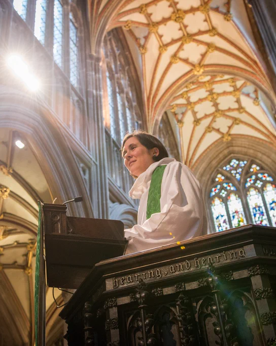 Woman priest stands in a pulpit.