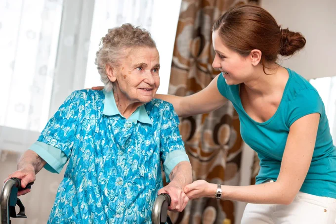 Younger woman supports older woman in a house