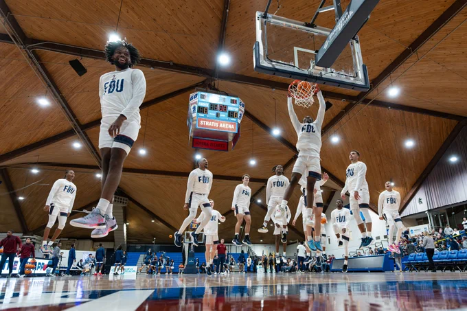 A team of basketball players all jump at the same time on a court.