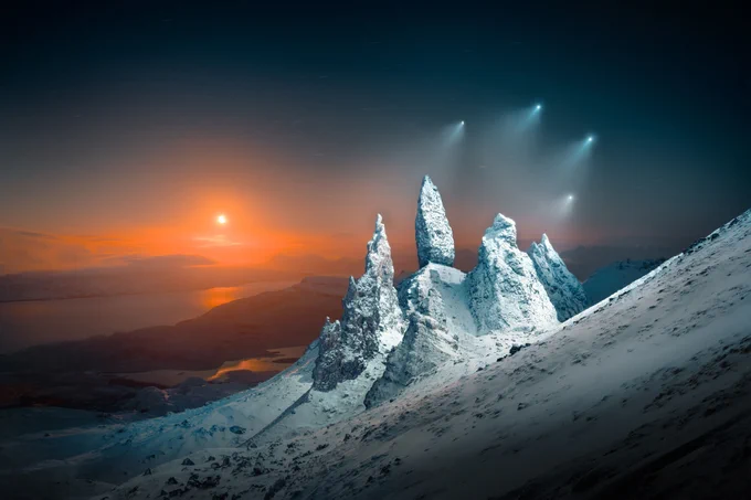 Four drones shine bright lights onto a cluster of snow-covered spires on a mountainside at moonrise.