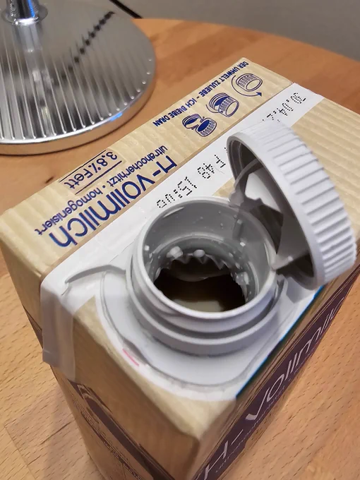 Ein Getränkekarton, von schräg oben aufgenommen, mit aufgeklapptem Tethered-Caps-Verschluss. Die gesamte Verpackung sollte mit all ihren Bestandteilen im Gelben Sack oder der Gelben Tonne entsorgt werden, damit sie bestmöglich recycelt werden kann.
