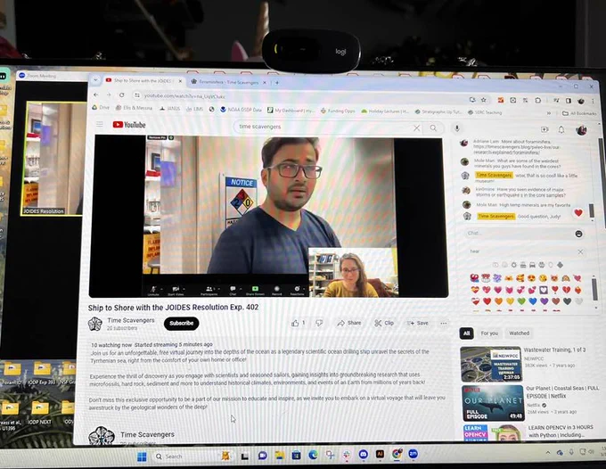 An image of a desktop screen. The screen is of a livestream on YouTube, with a man describing the science he is going.  A woman is shown listening in a small box on the bottom right corner of the screen. 