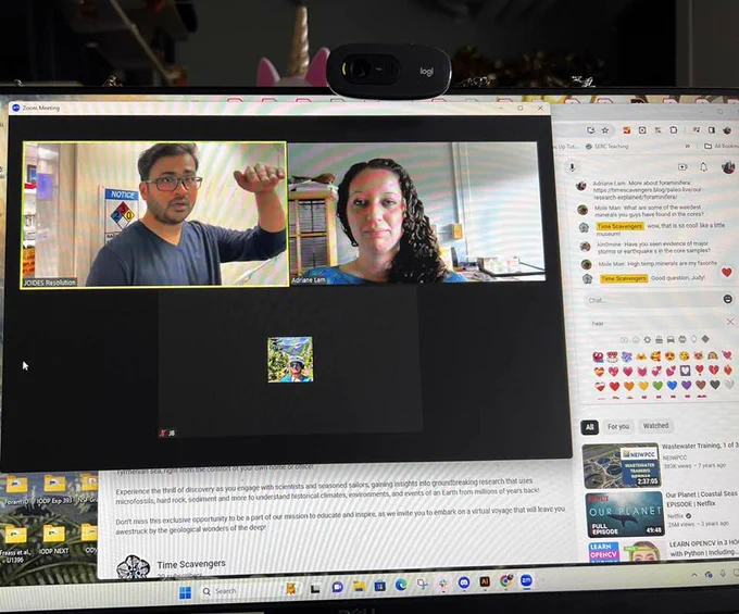 An image of a desktop computer. The foreground screen is of a man talking, with a woman listening. 