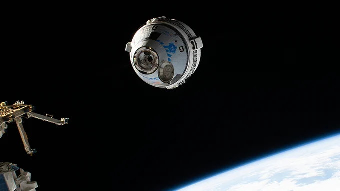 A spacecraft approaches the International Space Station. Part of Earth’s surface can be seen below.