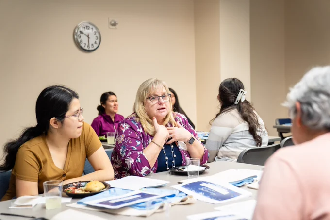 Close up of two groups of Project TLC participants sitting at tables talking together