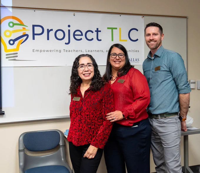 Three Project TLC staff members smiling and posing in front of the Project TLC banner