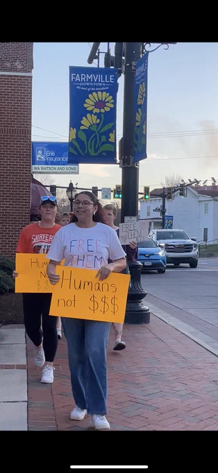 Students walk to the prince edward county meeting with orange signs demanding the town invest in life and not destructive institutions like detention on the way to testify at the meeting.
