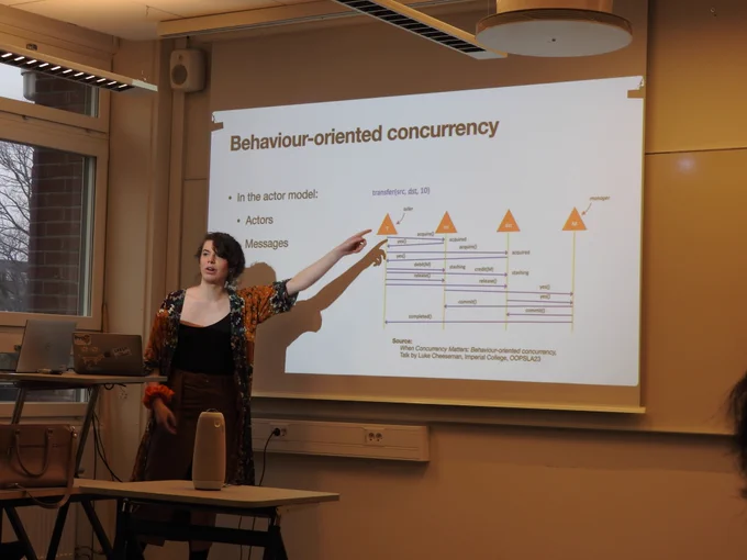 Photo of the VIMPL keynote. The speaker is pointing to a diagram on the slides behind them.