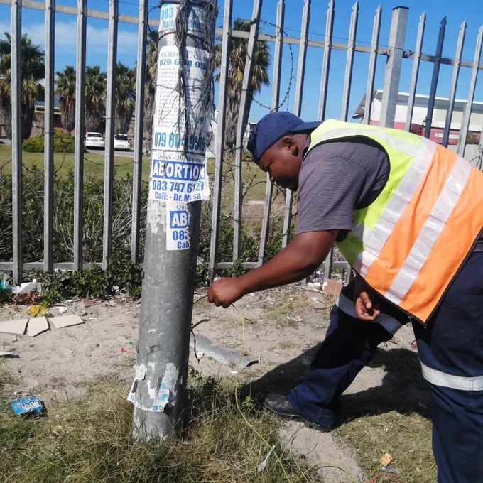 City official inspects vandalised streetlight.