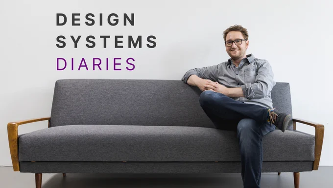 Johannes Lehner, seated casually with his legs crossed on a grey mid-century modern couch wearing glasses, a grey shirt, and jeans. Behind him, the title of the webinar series 'DESIGN SYSTEMS DIARIES' is displayed in large, bold font, with 'DESIGN SYSTEMS' in black and 'DIARIES' in purple.