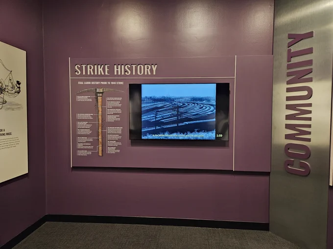 An infographic depicts the history of the 1946 coal strike. An adjacent monitor is playing a short interpretive film.
