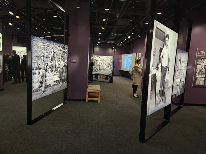 People walk through a series of large exhibit panels sharing the black and white photographs of Russell Lee.