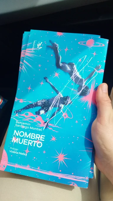 Portada del libro "Nombre muerto", de Benjamín Santiago Montiel, con prólogo de Violeta Niebla. La portada tiene dos niños flotando sobre el papel, que se ven de color blanco y negro y no se les distingue el rostro. El libro tiene fondo azul y destellos fucsia con forma de estrellas. A los niños los rodea un halo violeta.