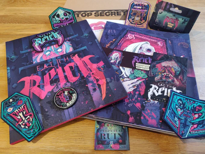 A photograph of the RPG book Eat the Reich, along with character sheets, an envelope marked top secret, and various patches