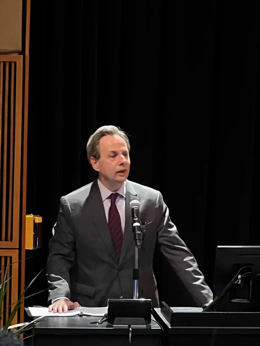 Dr. Michael Atchison, a Communication department alumni for his BA, emceed the event. This is the third year in a row he has done so. He is in a grey suit jacket and red tie.