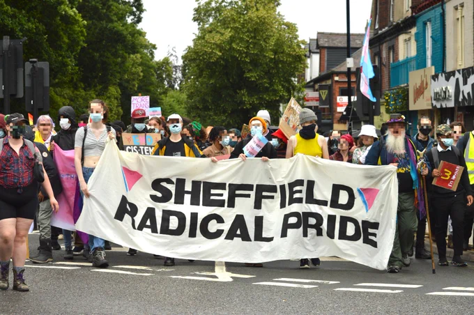 a crowd of people marching behind a banner reading "sheffield radical pride"