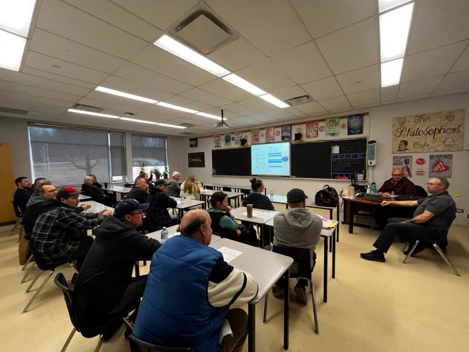 People sitting in a classroom listening to a discussion.